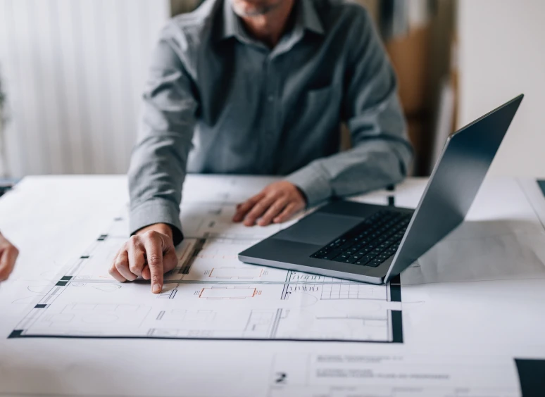 Person pointing at architectural plans on desk